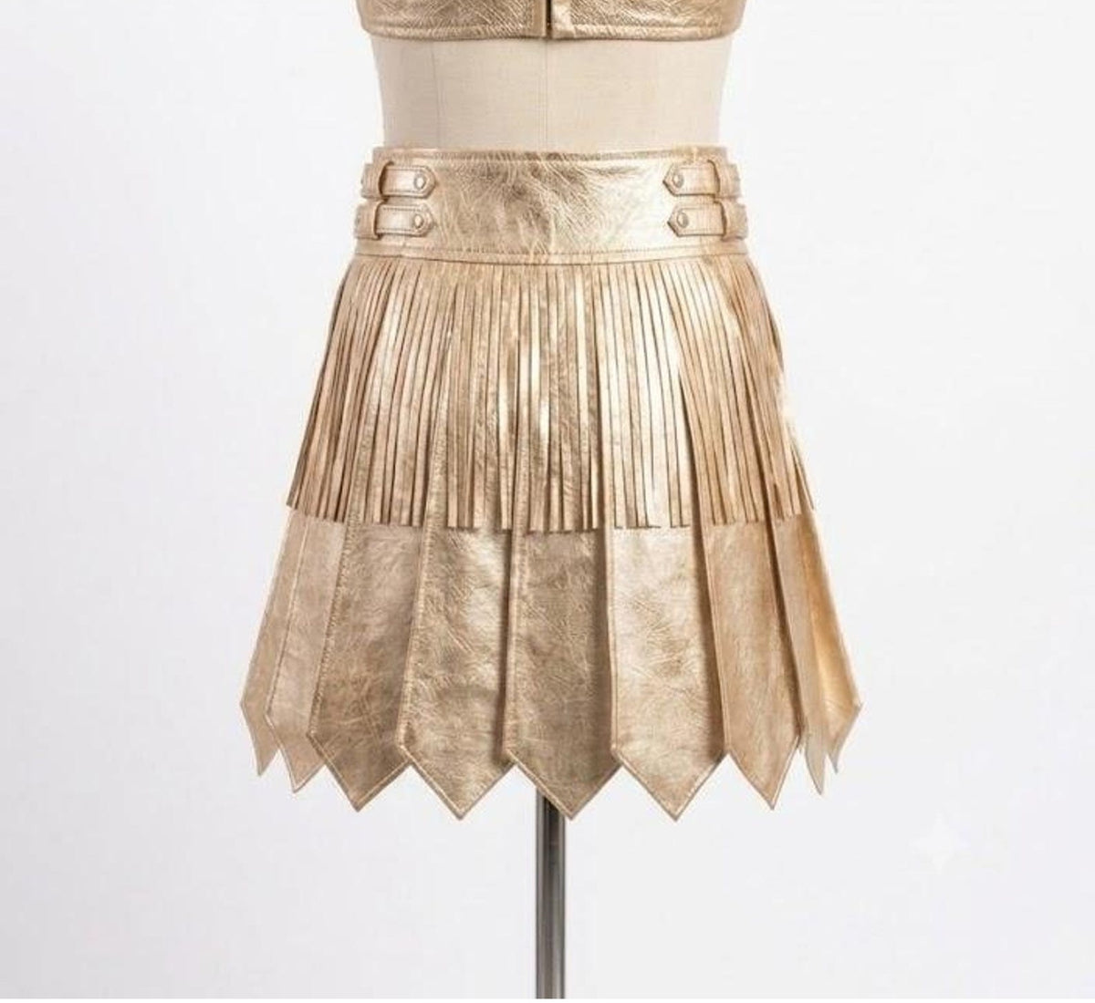 Back view of a gold gladiator kilt featuring a metallic finish, pleated design, and pointed hem panels